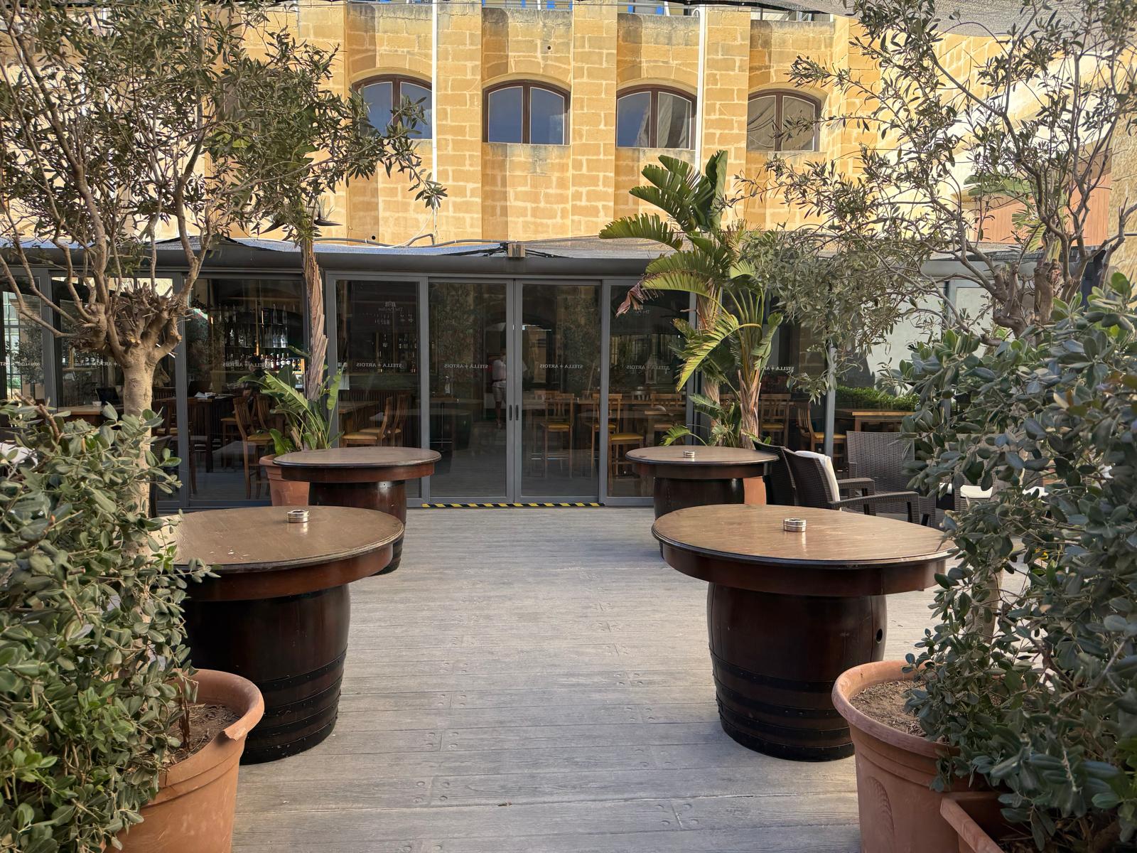 Trees and outdoor tables on the sunlit Kordin terrace
